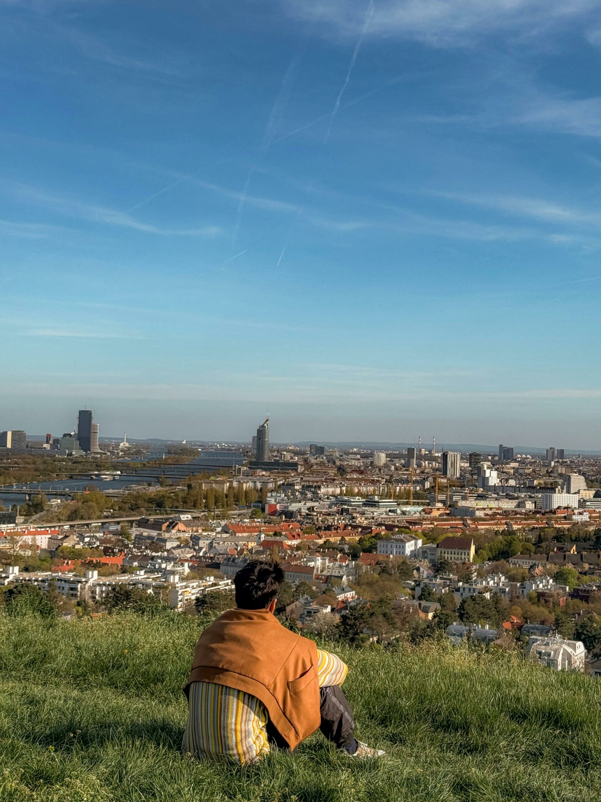 un jeune homme assis sur une colline regarde l'horizon, en direction de la ville